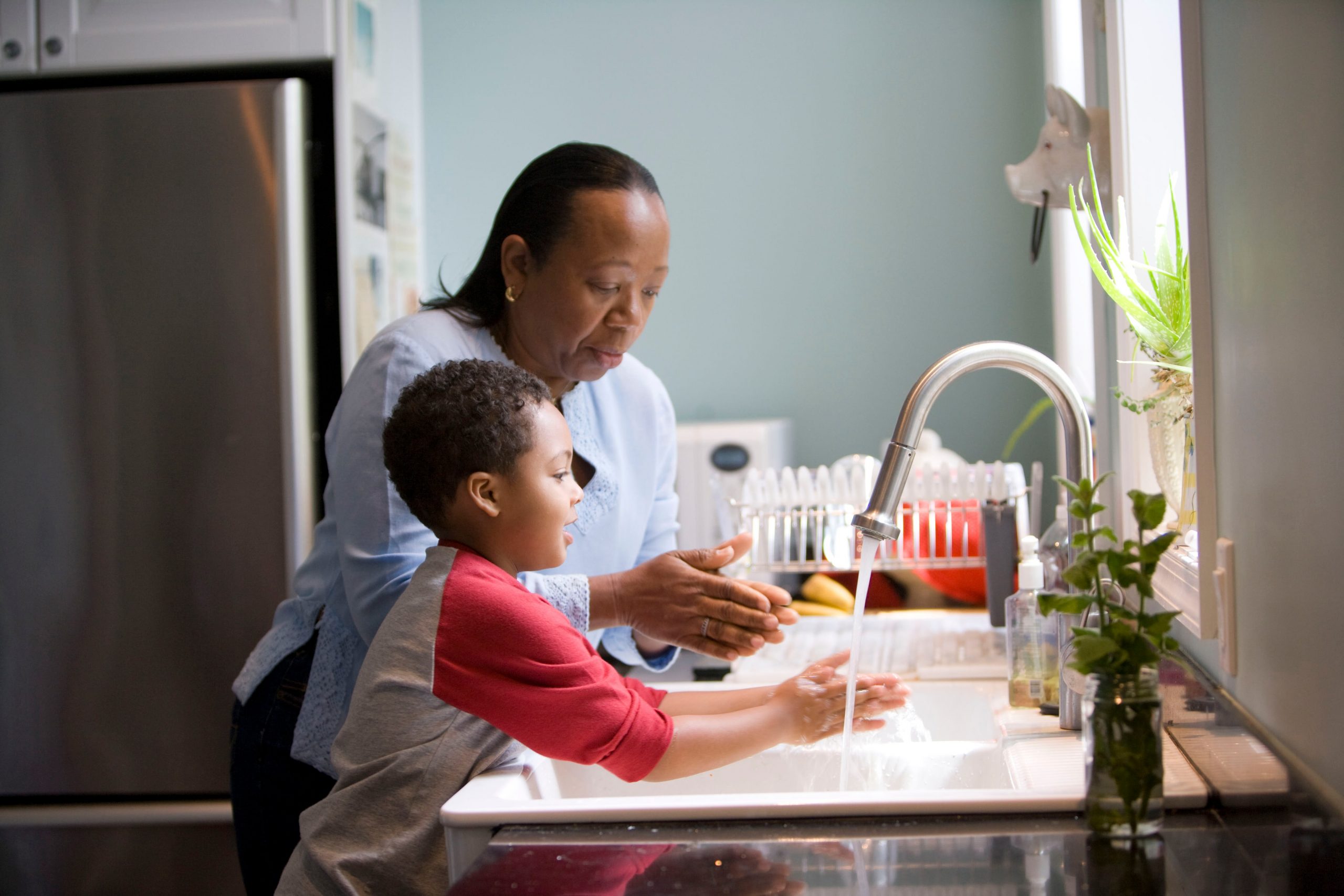 Adult woman and male child washing hands