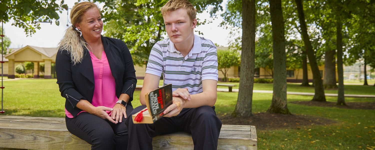 Female staff member and adolescent male client with book