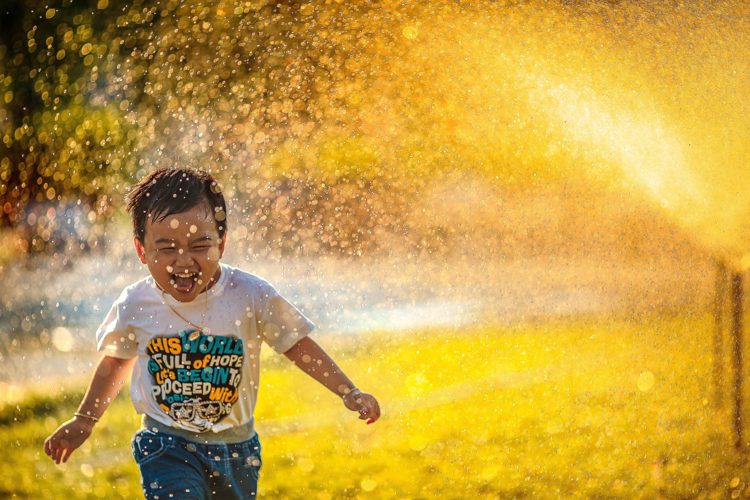 Young boy running through sprinkler