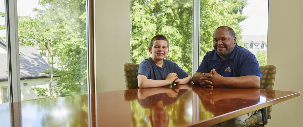 Adolescent male client and male staff member smiling