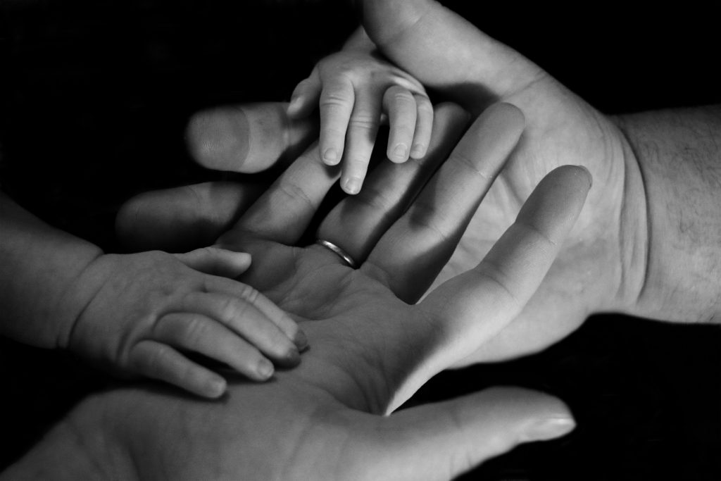 Baby's hands holding parents hands