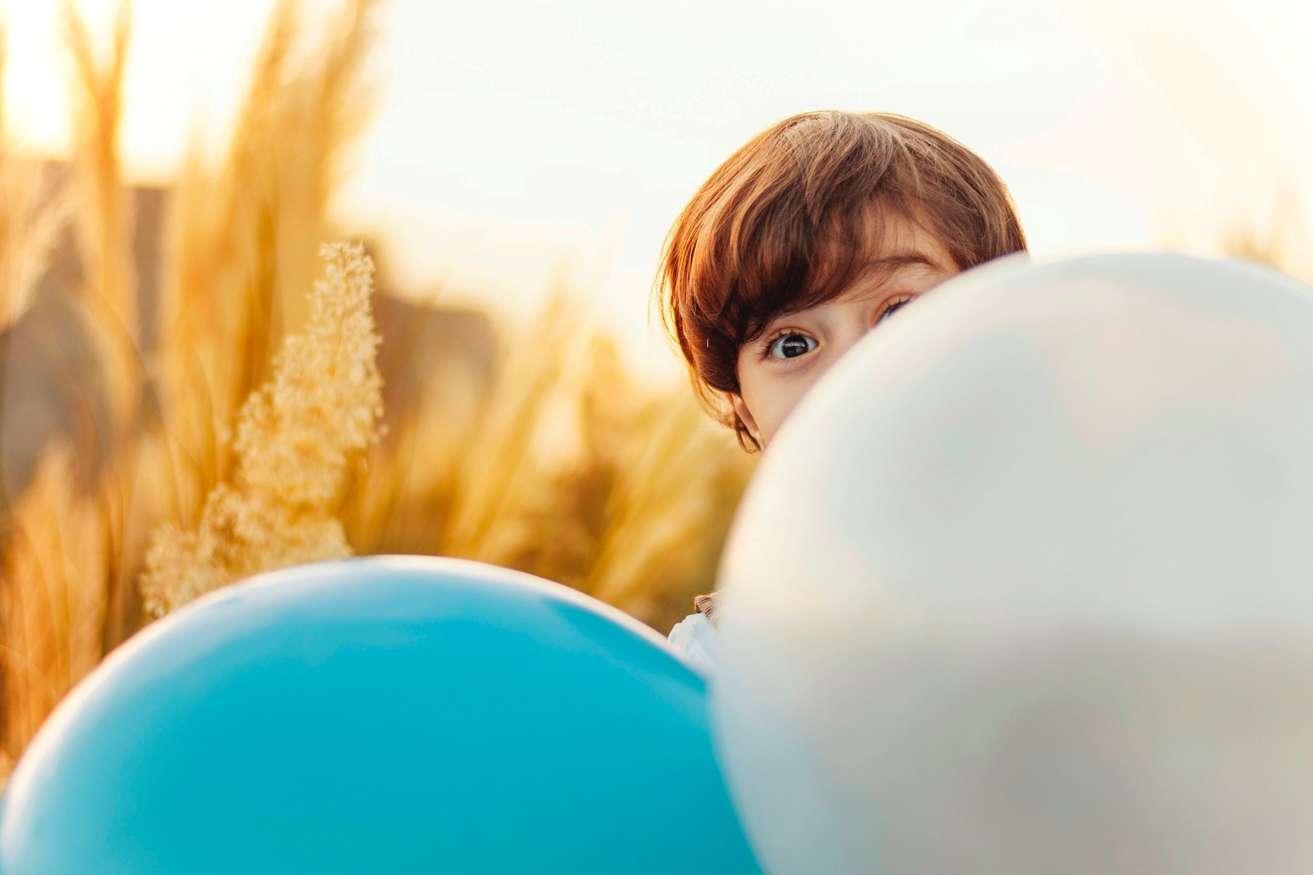 child hiding behind a balloon